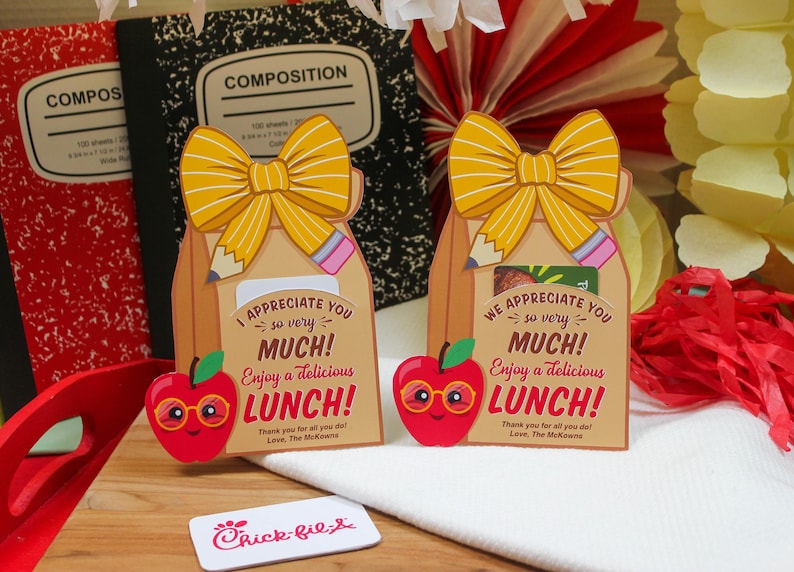 May include: Two brown paper bag gift bags with yellow bows and pencils sticking out of the top. The bags have a red apple with glasses on the front and say "I appreciate you so very much! Enjoy a delicious lunch!" and "We appreciate you so very much! Enjoy a delicious lunch!"