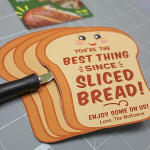 May include: A card shaped like a slice of bread with the text "You're the best thing since sliced bread! Enjoy some on us! Love, The McKowns".