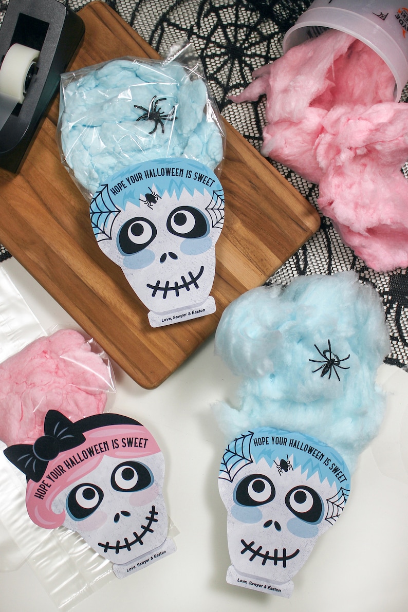 Puede incluir: Tres bolsas de algod&oacute;n de az&uacute;car con tem&aacute;tica de Halloween con etiquetas en forma de calavera. Las etiquetas tienen el texto "Espero que tu Halloween sea dulce" y un dise&ntilde;o de telara&ntilde;a. Una etiqueta tiene una calavera rosa con un lazo negro, otra tiene una calavera azul con una ara&ntilde;a negra y la &uacute;ltima tiene una calavera blanca con una ara&ntilde;a negra.