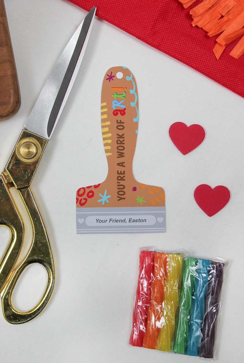 May include: A craft-themed image featuring a paint brush-shaped card with the text "YOU'RE A WORK OF ART!" and "Your Friend, Easton". Two red heart cutouts, a pair of gold scissors, and a package of rainbow-colored craft sticks are also visible.