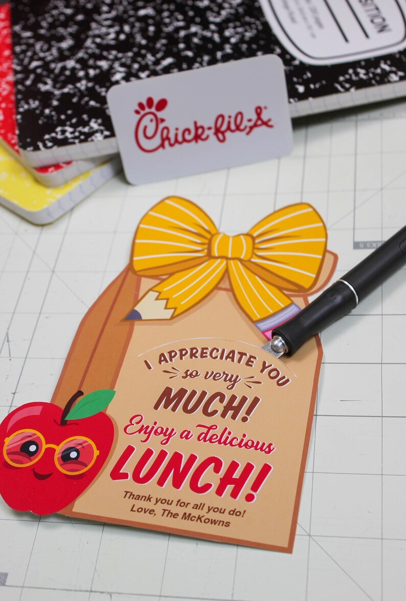 May include: A brown paper lunch bag with a yellow bow and a red apple with glasses. The bag has the text "I appreciate you so very much! Enjoy a delicious LUNCH! Thank you for all you do! Love, The McKowns".