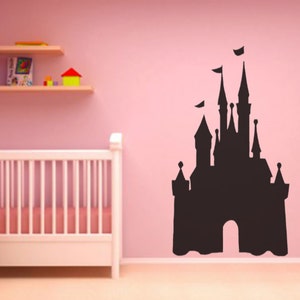 May include: A black silhouette of a fairytale castle on a pink wall. The castle has many towers and a large arched entrance. The silhouette is a wall decal.