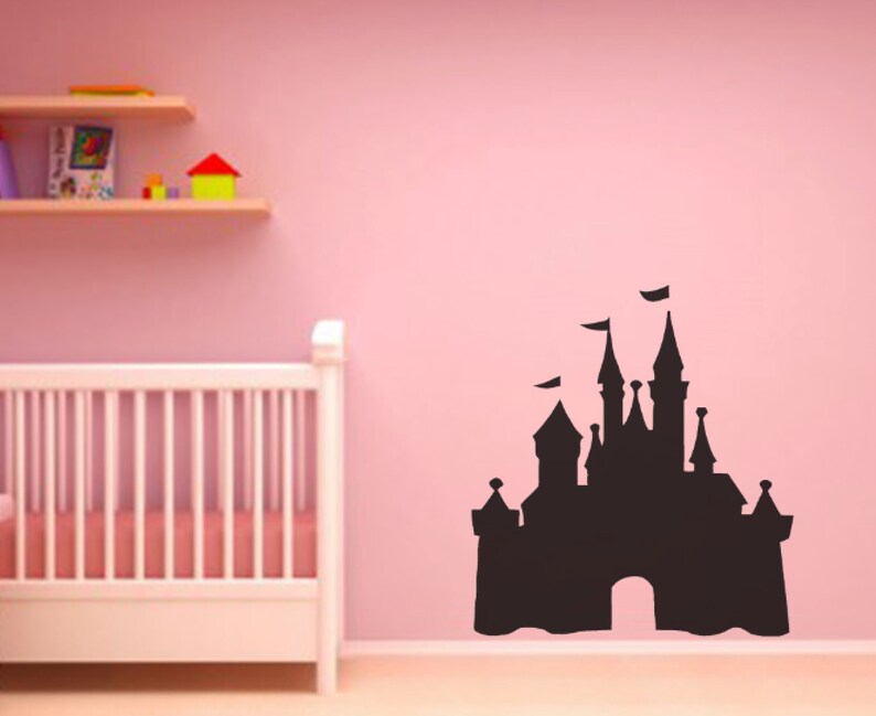 May include: Black silhouette of a fairytale castle on a pink wall. The castle has a large archway and multiple towers. The silhouette is a wall decal.