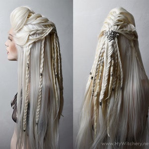 May include: A long platinum blonde wig featuring intricate braided sections, loose flowing hair, and textured dreadlocks. The hairstyle is adorned with silver-toned metal beads and a decorative silver hair clip. Text reads www.MyWitchery.net.