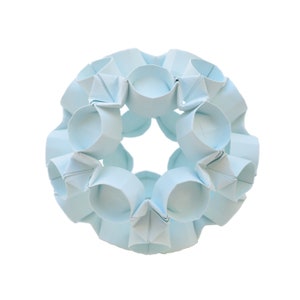 May include: A light blue origami sphere made of folded paper. The sphere is made up of many small, folded units that create a complex and intricate design.