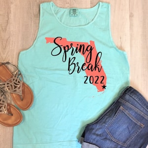 May include: A turquoise tank top with a coral outline of the state of Florida and the text "Spring Break 2022" in black.