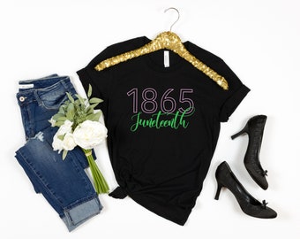 May include: Black t-shirt with the text "1865 Juneteenth" in green and pink lettering.