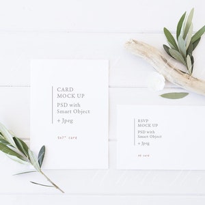 Puede incluir: Dos tarjetas blancas sobre una superficie de madera blanca con ramas verdes y un trozo de madera a la deriva. La tarjeta de la izquierda dice "CARD MOCK UP PSD with Smart Object + Jpeg 5x7" card. La tarjeta de la derecha dice "RSVP MOCK UP PSD with Smart Object + Jpeg 4x6" card.