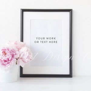 Op de afbeelding: Een zwarte fotolijst met een witte passe-partout en een witte achtergrond. De lijst staat op een wit oppervlak. De tekst "Your work or text here" is in zwart op de witte achtergrond gedrukt.