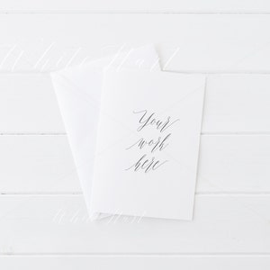Puede incluir: Una tarjeta blanca con el texto "Your work here" escrito en caligraf&iacute;a negra sobre un fondo de madera blanca.