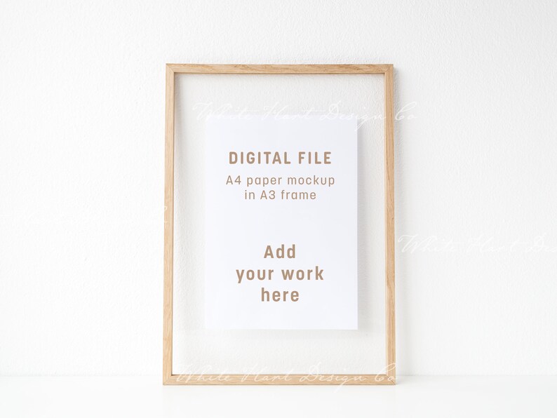 Pu&ograve; includere: Una cornice A3 in legno chiaro con un mockup di carta A4 bianca. Il testo sulla carta recita "DIGITAL FILE, A4 paper mockup in A3 frame, Add your work here."
