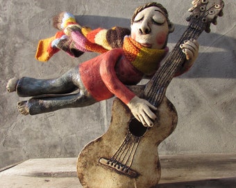 Ceramic Flying Guitarist wearing a hand knitted striped Scarf