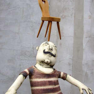 Ceramic Juggler balancing a hand carved chair