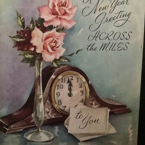 May include: Vintage New Year's greeting card with a watercolor illustration. Features pink roses in a silver vase, a clock at midnight, and the text "A New Year Greeting ACROSS the MILES" and "to You".