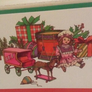 May include: A vintage Christmas card illustration featuring a pink toy wagon with the word "ICE" on the side, a toy horse pulling the wagon, a toy drum, a doll with a pink dress, and wrapped presents.