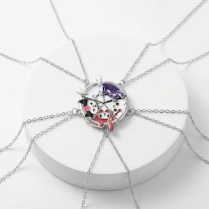 May include: A set of five silver-toned friendship necklaces. Each necklace features a circular pendant divided into five sections, each with a different cartoon character in red, black, white, and purple. The pendants are connected to delicate chain necklaces.