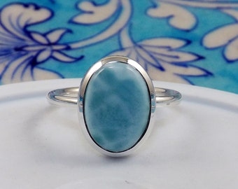 May include: A silver ring with a light blue oval-shaped gemstone. The gemstone has a swirling pattern.