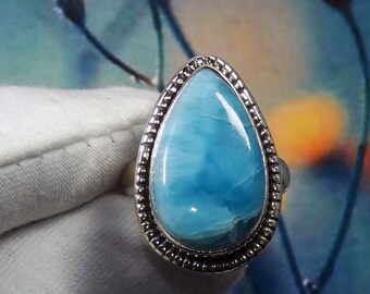 May include: A teardrop-shaped ring with a blue and white gemstone set in a silver band.