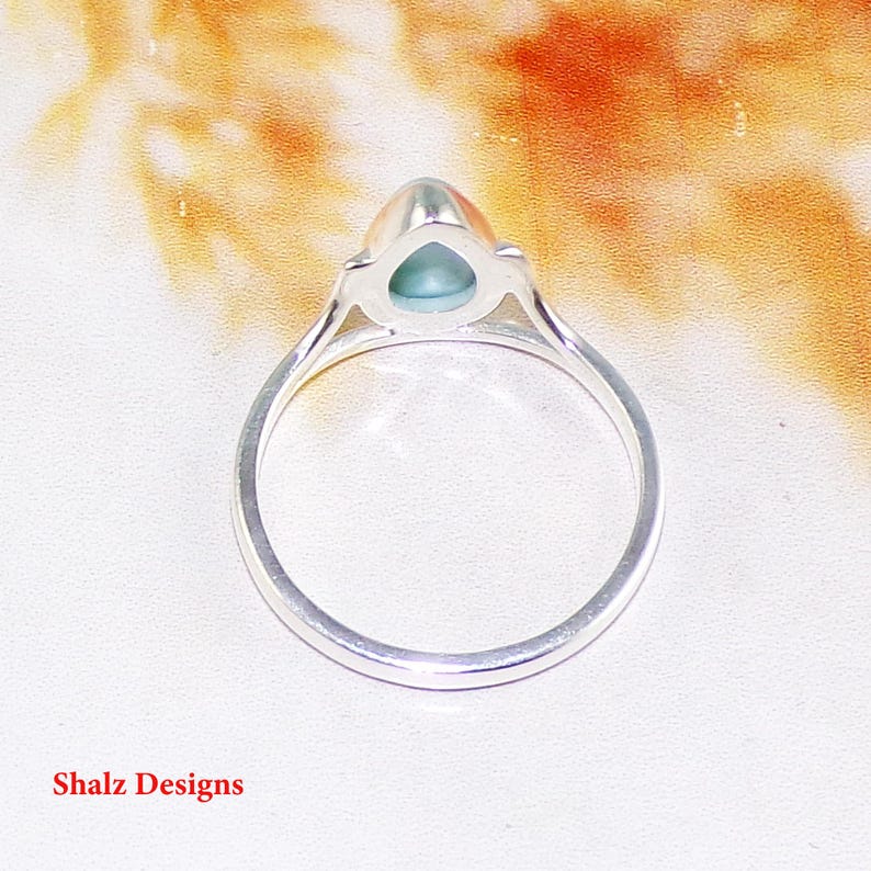 May include: A silver ring with a teardrop-shaped green gemstone.