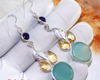 Puede incluir: Pendientes de plata con piedras preciosas azules y amarillas. Los pendientes tienen un diseño de hoja y una piedra preciosa redonda grande de color azul claro.