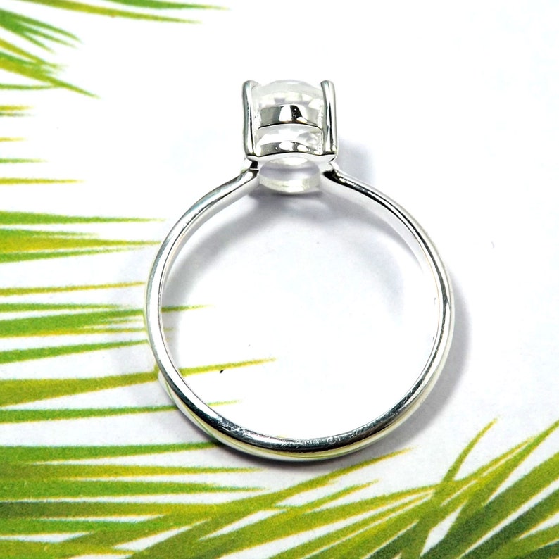 May include: A silver ring with a clear gemstone set in a prong setting.