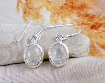 May include: A pair of silver dangle earrings with oval-shaped moonstone gemstones. The earrings have a simple design and are perfect for everyday wear.