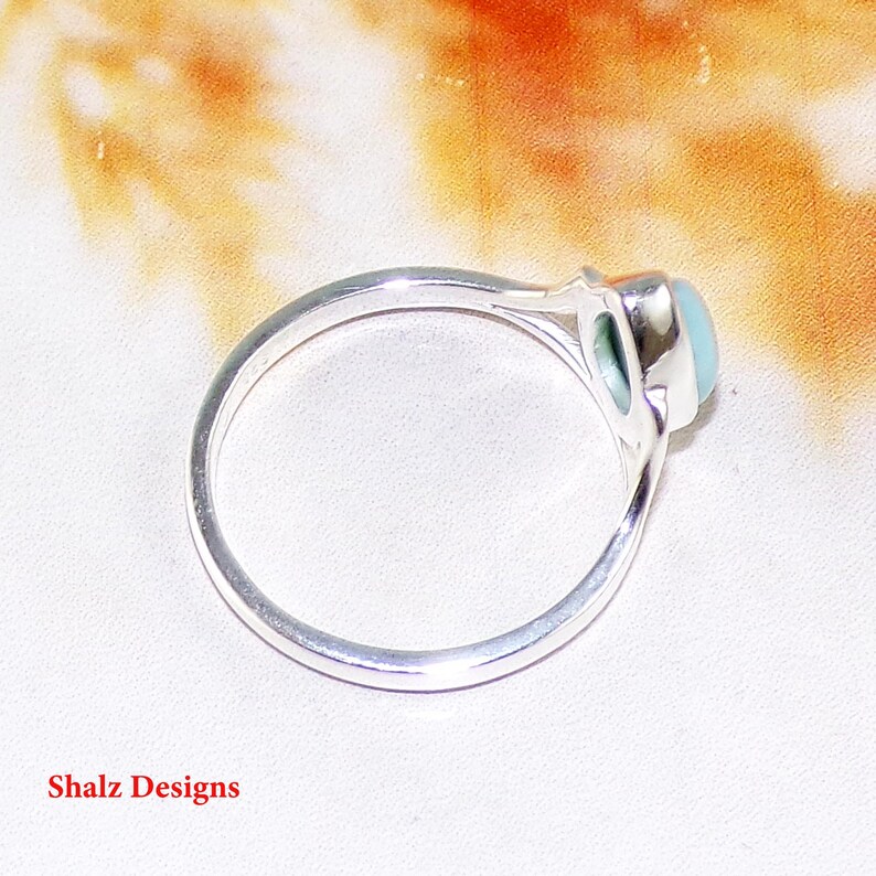 May include: A silver ring with a light blue oval gemstone set in a bezel setting.