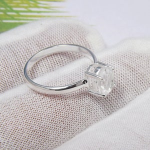 May include: A silver ring with a clear, faceted gemstone set in a cage-like setting.