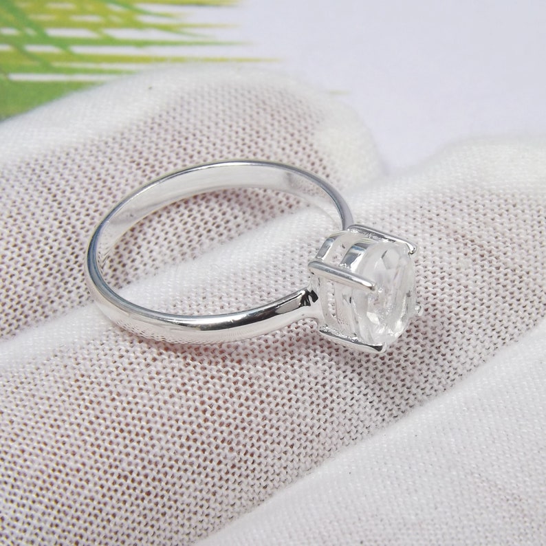 May include: A silver ring with a clear, faceted gemstone set in a cage-like setting.