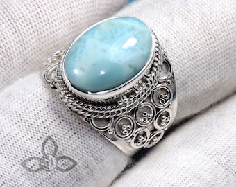 May include: A silver ring featuring a large oval blue gemstone set in a detailed silver band. The band has a rope-like design and a row of small circles.