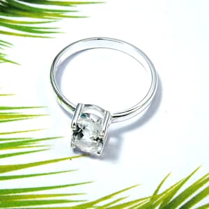 May include: A silver ring with a clear round gemstone.