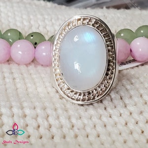 Puede incluir: Un anillo de plata con una gran piedra de luna ovalada engastada en una banda de plata retorcida.