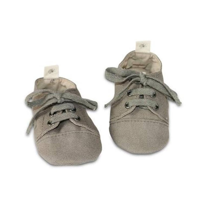 May include: A pair of small, gray canvas shoes with gray laces. The shoes have a classic sneaker design, with a rounded toe and a small tag on the tongue. The shoes are likely for a baby or toddler.