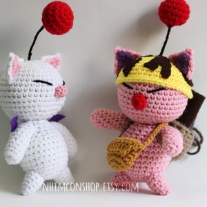 May include: Two crocheted plushies, one white with a red ball on top and purple accents, and one pink with a yellow hat and brown accents. Both plushies have a red nose and closed eyes.
