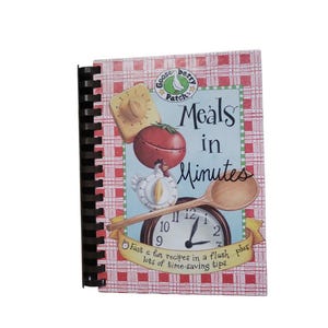 May include: A spiral-bound cookbook titled Meals in Minutes by Gooseberry Patch. The cover features a red and white checkered pattern, a tomato-shaped timer, a chicken-shaped timer, a wooden spoon, and a clock with the text Fast & fun recipes in a flash plus lots of time-saving tips.