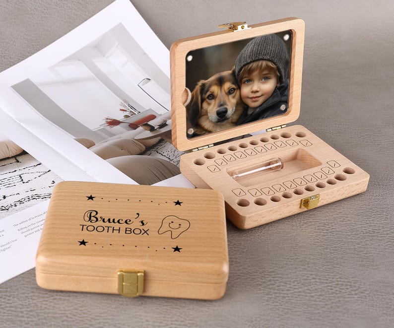 May include: Wooden tooth box with a hinged lid and a gold-colored clasp. The box is engraved with the text "Bruce's TOOTH BOX" and a smiling tooth graphic. The open box has a clear photo of a child and a dog.