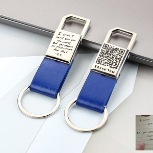 May include: Two blue leather keychains with silver metal accents. One keychain has a QR code and the text "I Love You". The other keychain has a handwritten message that reads "I wish I could give you the world, But you deserve so much more than that -J.T."