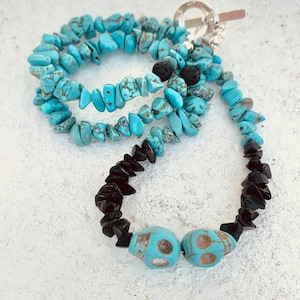 May include: A layered necklace featuring turquoise chip beads and black onyx chips. The necklace includes two turquoise skull beads and a silver toggle clasp. The turquoise beads have brown matrix patterns.