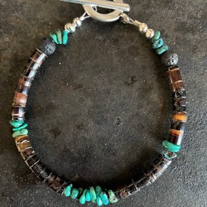 May include: A turquoise, brown and black beaded bracelet with a silver toggle clasp.