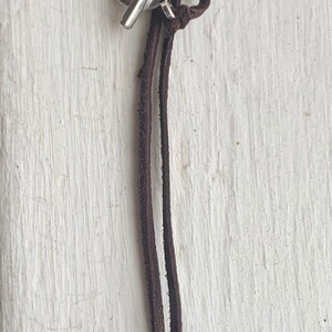 May include: A brown leather cord necklace with a silver toggle clasp and a brown and white tooth pendant.