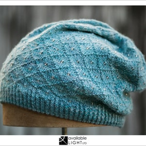 May include: A blue knitted beanie with a textured pattern and small silver embellishments.
