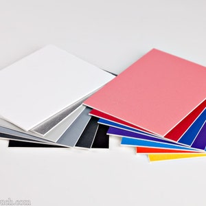 May include: A set of colorful and neutral colored paper squares, perfect for photography backdrops. The squares are arranged in a fan shape, with the white square on top and the yellow square on the bottom.
