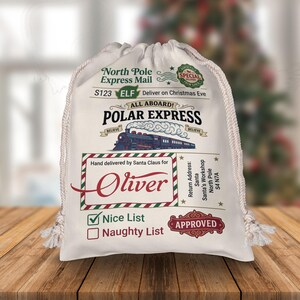 May include: A white drawstring canvas sack featuring North Pole Express Mail graphics, a Polar Express train illustration, and the name Oliver printed in red. The bag includes a Nice List checkbox, a Santa's Workshop return address, and an Approved stamp.