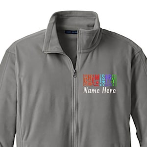 May include: A gray fleece jacket with a full zipper and a stand-up collar. The jacket features the text "CHEMISTRY" in a colorful, stacked design, with "Name Here" below. The jacket has two side pockets.