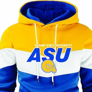 May include: A hooded sweatshirt in yellow, white, and blue, featuring the text "ALBANY STATE UNIVERSITY" and "ASU" in white and blue. The sweatshirt has a drawstring hood and a graphic of a ram's head.