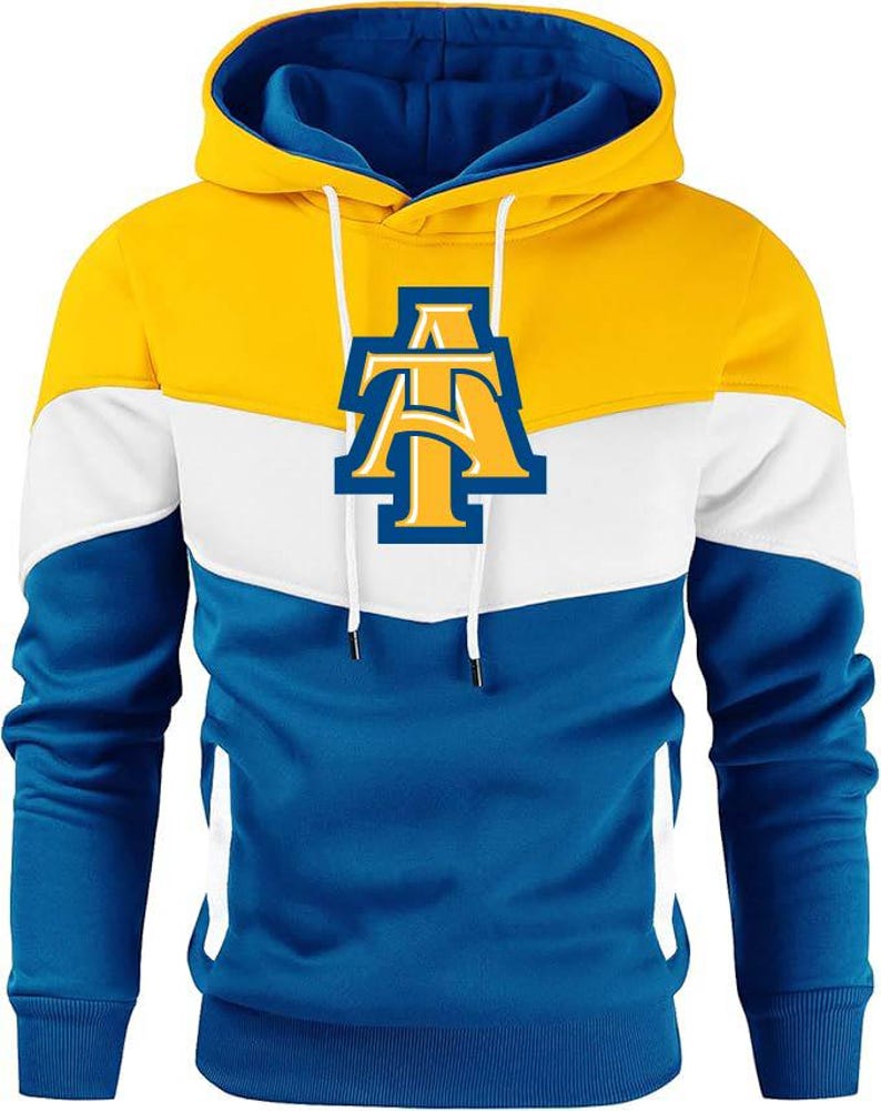 May include: A hooded sweatshirt in yellow, white, and blue. The top section is yellow, transitioning to white, then blue. The hood is blue inside. A logo with the letters "AT" is on the chest.