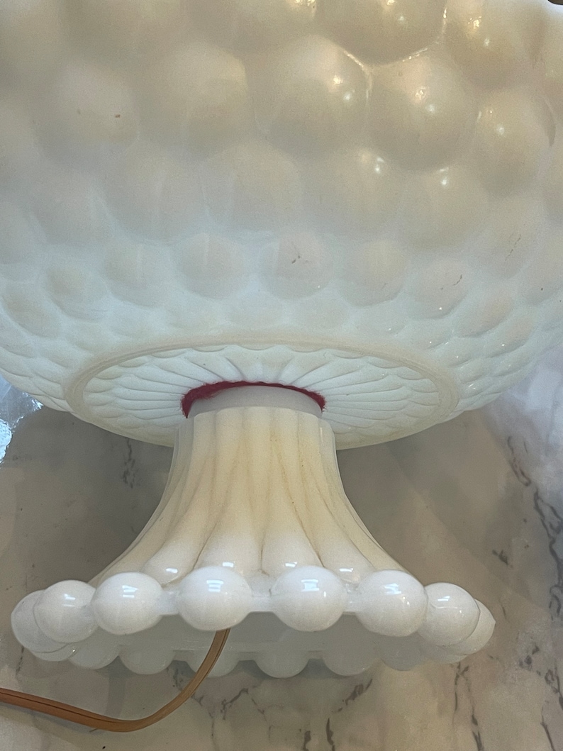 May include: White milk glass lamp base with a textured bubble design. The base has a fluted pedestal and a scalloped bottom edge.
