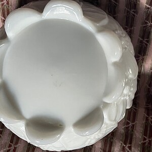May include: White milk glass bowl with a scalloped edge and floral design. The bowl is empty and has a smooth, glossy finish.