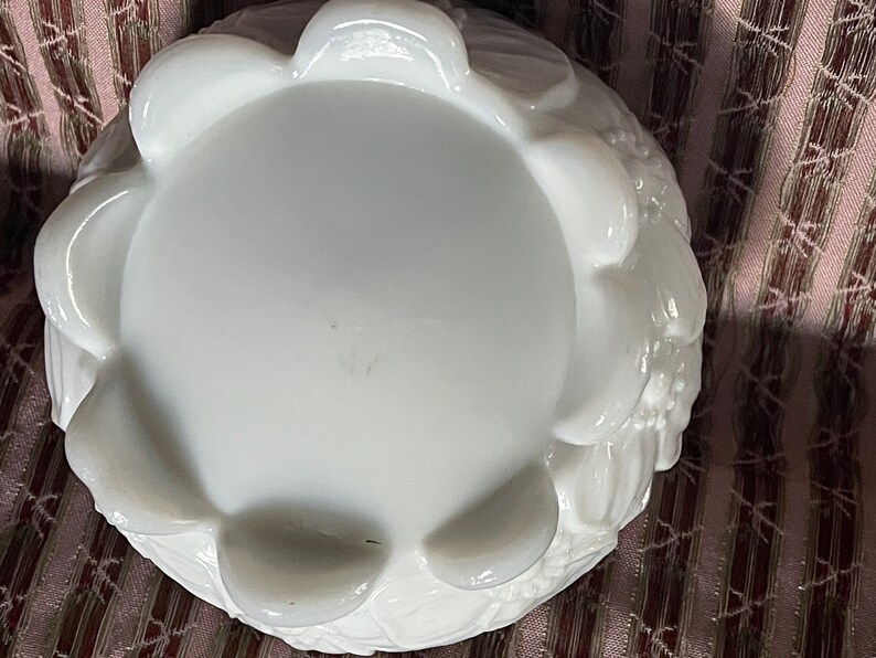 May include: White milk glass bowl with a scalloped edge and floral design. The bowl is empty and has a smooth, glossy finish.