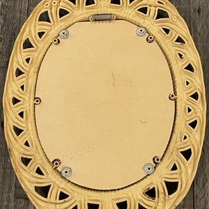 Puede incluir: Un espejo grande de forma ovalada con un marco decorativo y ornamentado. El marco est&aacute; hecho de un material beige claro y tiene un dise&ntilde;o delicado e intrincado. El espejo est&aacute; rodeado por un fino borde plateado.